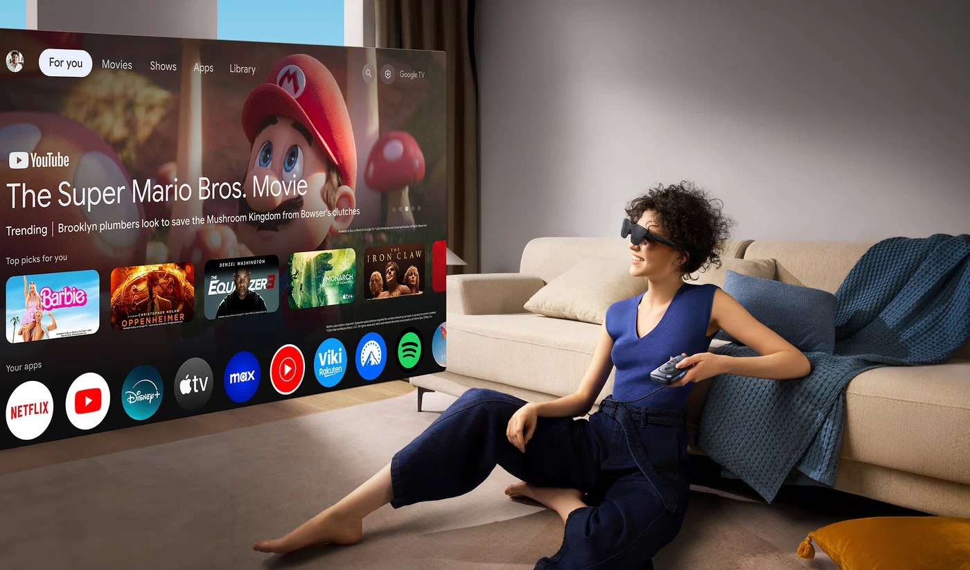 A person wearing RayNeo GT glasses while watching a large virtual screen
